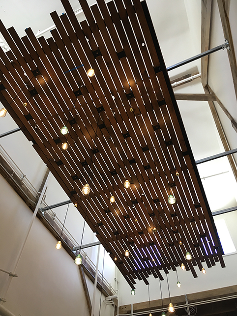 Looking up at the custom wood light fixtures made of old pallets that hang from the ceiling of the breezeway